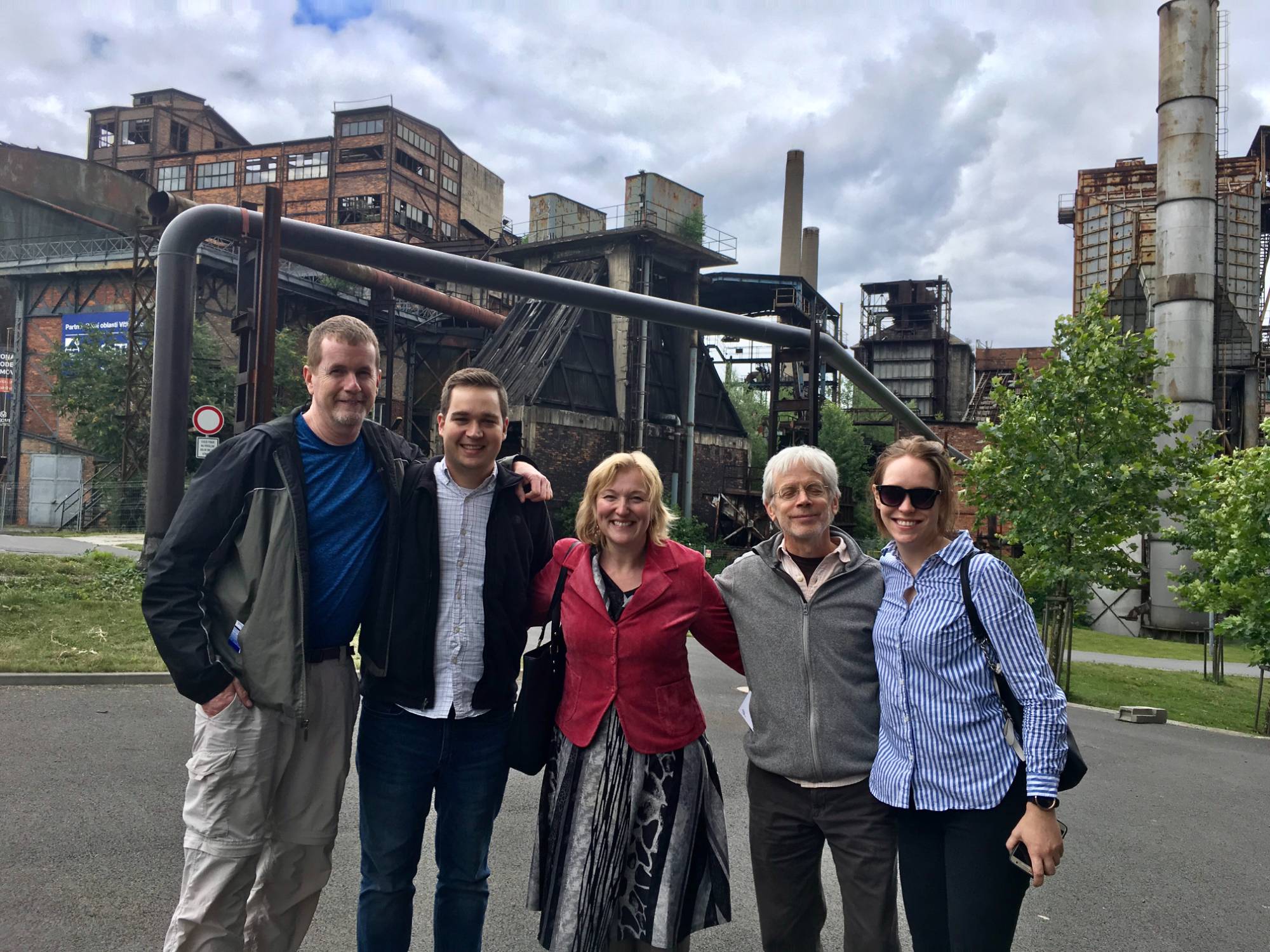 A photos of the Grand Valley Winds ensemble in front of old steel construction.